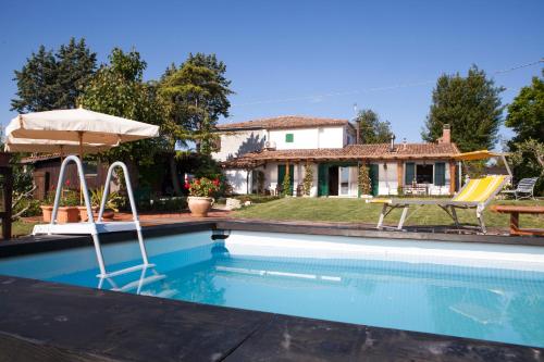 uma piscina com duas cadeiras e um guarda-sol e uma casa em Casa S.Paolo em Rimini
