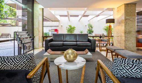 a living room with a couch and tables and chairs at H4 La Residence Paulista in Sao Paulo