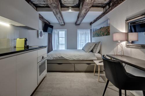a bedroom with a bed and a desk and a kitchen at smartroom The Residence la Cittadella Baden in Baden