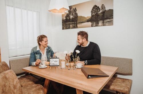 a man and woman sitting at a table with a laptop at Appartements Almnest in Schladming