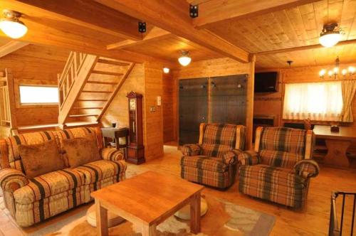 a living room with two couches and a table at Log Cottage Epoch in Hakuba