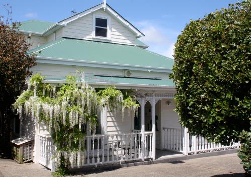 a white house with a blue roof and a white fence at The Great Ponsonby Arthotel in Auckland