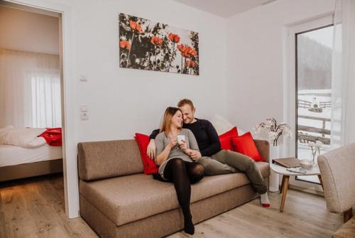 a man and a woman sitting on a couch at Appartements Almnest in Schladming
