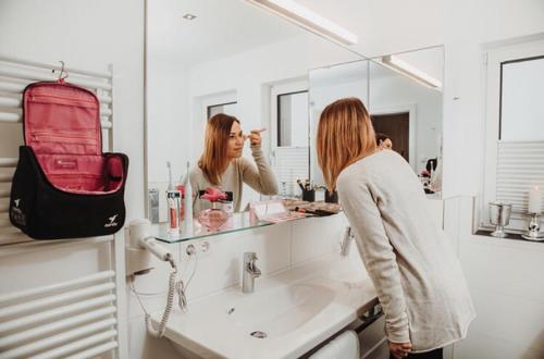 a woman looking at her reflection in a bathroom mirror at Appartements Almnest in Schladming