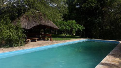 a swimming pool with a hut with a bench and a table at Shankara Rest Camp in Makena