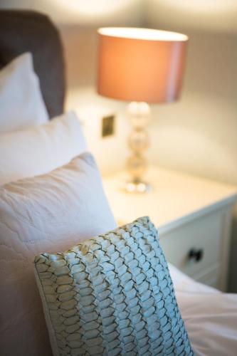 a bed with a pillow and a lamp on a table at Lamlash Bay Hotel in Lamlash