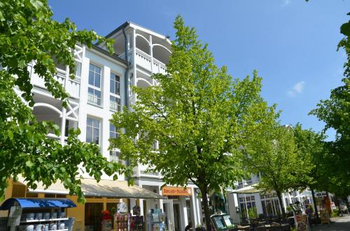 um edifício branco numa rua com árvores em frente em Seepark Sellin - Apt. 449 em Ostseebad Sellin