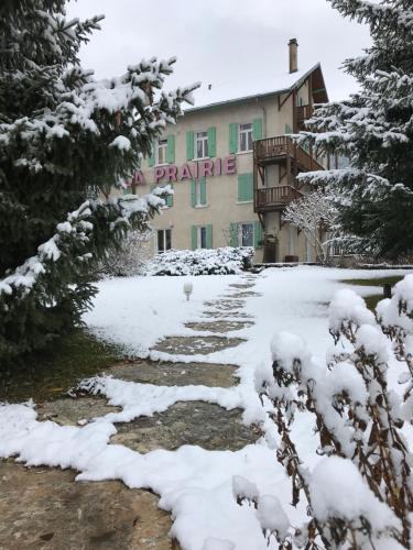 a snow covered path in front of a building at Hotel La Prairie in Méaudre