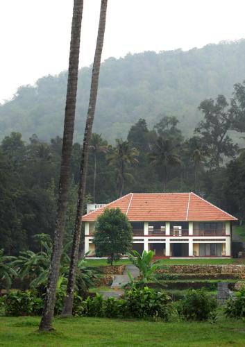 a house with a red roof and some palm trees at Windermere River House in Neriyamangalam