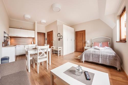 a bedroom with a bed and a dining room at Rezydencja Park, Sun & Snow in Mielno