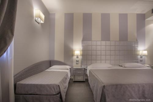 a room with two beds in a room with striped walls at Savoia Hotel Country House Bologna in Bologna
