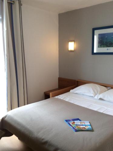 a hotel room with a bed with a magazine on it at Appart'hôtel Goélia Sun City in Montpellier