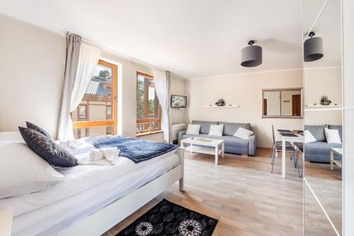 a bedroom with a bed and a living room at Rezydencja Park, Sun & Snow in Mielno