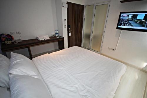a bedroom with a white bed and a flat screen tv at Nantra Ekamai Hotel in Bangkok