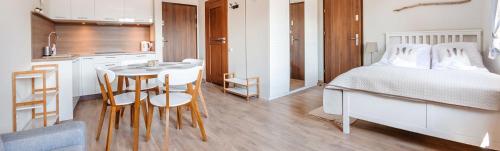 a kitchen and a bedroom with a bed and a table at Rezydencja Park, Sun & Snow in Mielno