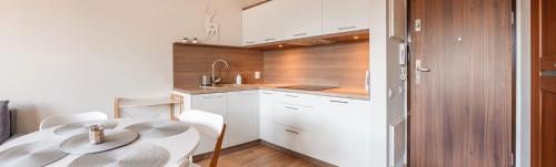 a kitchen with a table and white cabinets and a sink at Rezydencja Park, Sun & Snow in Mielno