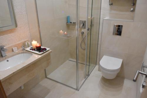 e bagno con servizi igienici e doccia con candele. di Alibi Zlatibor Inn a Zlatibor