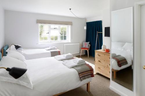 a bedroom with two beds and a mirror at Compasses Inn in Tisbury