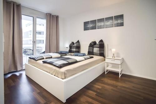 a white bedroom with a large bed and a table at Deluxe Ferienwohnung Apartment Stuttgart Centre/Milaneo in Stuttgart