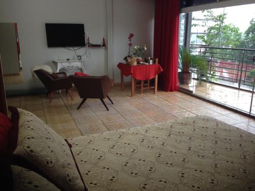a living room with a bed and a table and a television at Pousada Beira Rio in Itumbiara