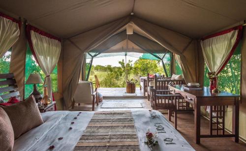 a tent with a bed and a desk in it at Losokwan Luxury Tented Camp - Maasai Mara in Aitong