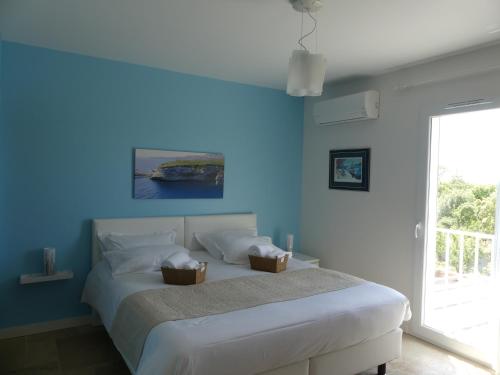 niebieska sypialnia z łóżkiem z dwoma koszami w obiekcie Maison d' Hôtes L'Aria Mezzana w mieście Sainte-Lucie de Porto-Vecchio