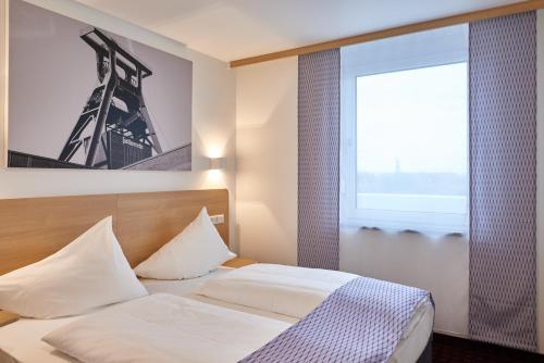 a bedroom with a bed and a large window at McDreams Hotel Essen in Essen