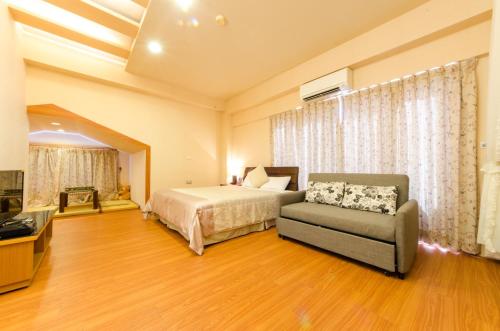 a bedroom with a bed and a couch and a tv at Yosemite Homestay in Yuanshan