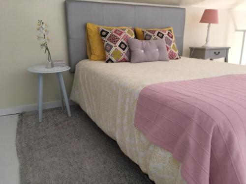 a bedroom with a pink bed with pillows and a table at Villa Atlantis in Calheta