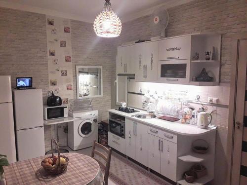 una cocina con electrodomésticos blancos y una mesa con un bol de fruta en apartamenti drevni batumi, en Batumi