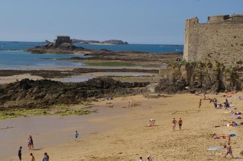 a group of people on a beach near a castle at Gîte Bambou in Saint-Lunaire