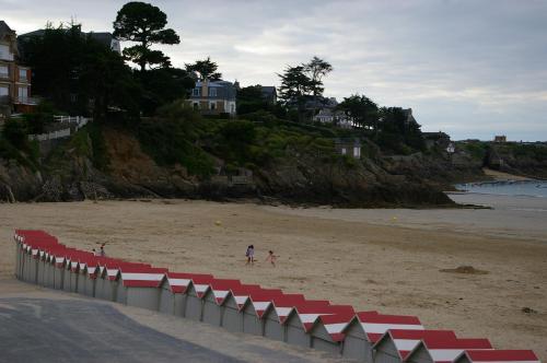 a beach with red and white dividers on the sand at Gîte Bambou in Saint-Lunaire