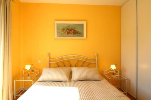 - une chambre dotée d'un lit avec un mur orange dans l'établissement Le Clos des Bouviers, à Lanton