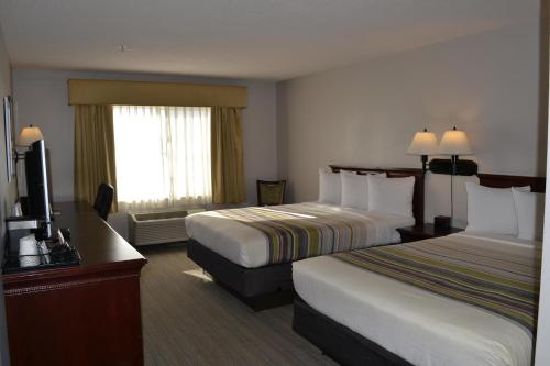 a hotel room with two beds and a flat screen tv at Country Inn & Suites by Radisson, Gurnee, IL in Gurnee