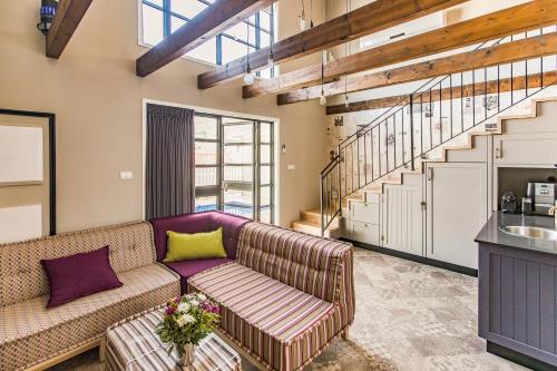 a living room with a couch and a staircase at Gold 68 in Kefar Barukh