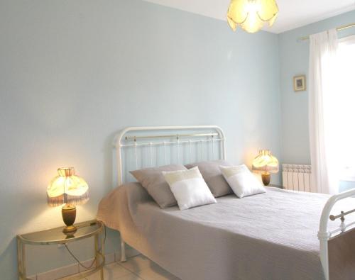 een slaapkamer met een wit bed en 2 lampen bij Jardin du Bourg in Lanton