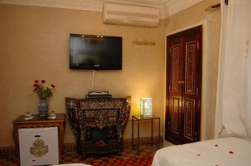 a room with a bed and a television on the wall at Riad Palais Des Princesses & Spa in Marrakesh