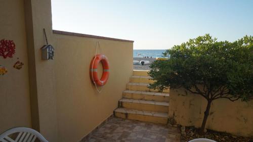 a set of stairs leading to a beach with a life preserver at Finestra sul Mare in Terme Vigliatore