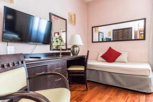 a small room with a bed and a desk with a television at Hotel Giolli Nazionale in Rome