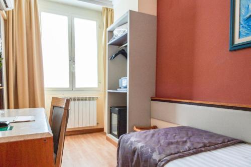 a room with a bed and a desk and a window at Hotel Giolli Nazionale in Rome