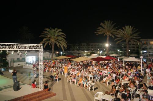 a large crowd of people sitting around a pool at night at El Mouradi Club Kantaoui in Port El Kantaoui