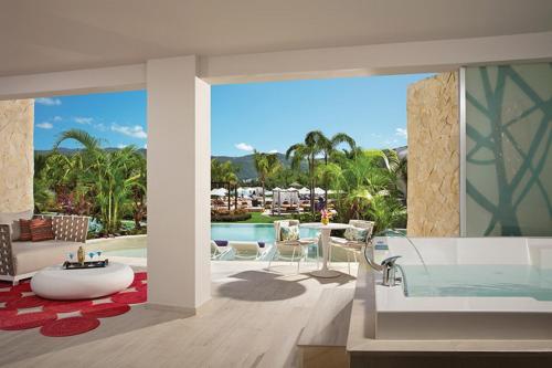 ein Badezimmer mit einer Badewanne und einem Pool in der Unterkunft Breathless Montego Bay in Montego Bay