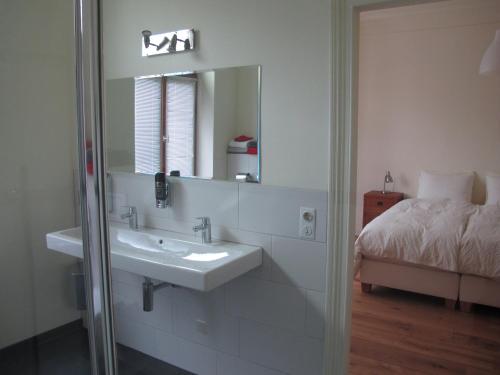 a bathroom with a sink and a mirror and a bed at Bed and Breakfast Allure in Vaals