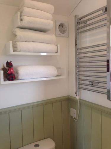 a bathroom with a stack of towels and a toilet at Upper Gilwern Quarry Hut in Llandrindod Wells