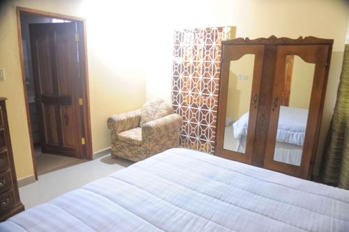 a bedroom with a bed and a chair and a mirror at Eagle's Nest in Montego Bay