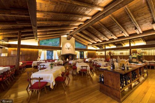 un restaurant avec des tables et des chaises blanches et des plafonds en bois dans l'établissement Albergo Ristorante Bucaneve, à Bielmonte