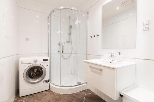 baño blanco con lavadora y lavamanos en Luxurious Apartments at Žižkov, en Praga