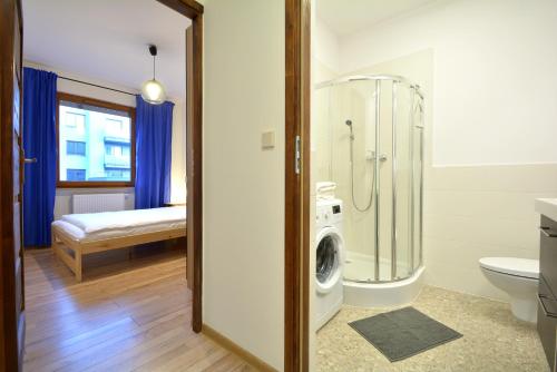 een badkamer met een douche en een wasmachine bij Apartament Bema 38 in Wrocław