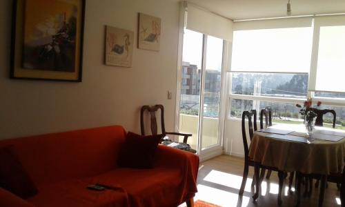 a living room with a table and a red couch at Lomas Papudo 4 in Papudo