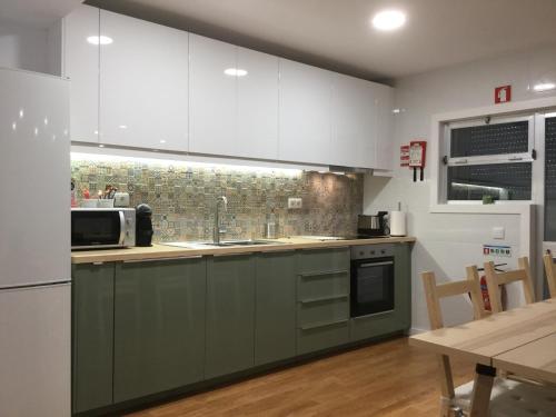 a kitchen with green and white cabinets and a table at My Portugal for All - Oporto Flat in Vila Nova de Gaia